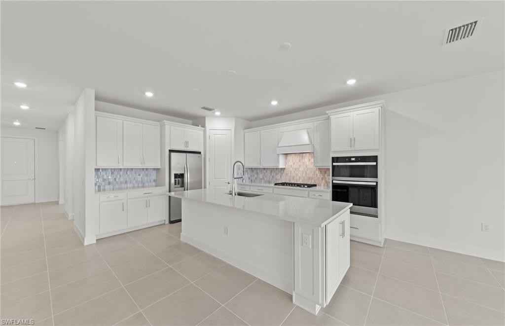 12404 Basalt Lane Alva, FL 33920 - Photo 24 of 50 a large white kitchen with stainless steel appliances and white cabinets