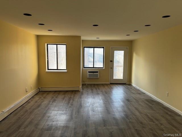 150-40 Tahoe Street, Unit 3C Queens, NY 11417 - Photo 13 of 18 Spare room with healthy amount of natural light, dark wood-type flooring, a baseboard heating unit, and an AC wall unit
