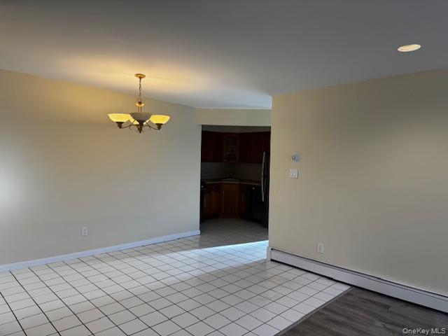 150-40 Tahoe Street, Unit 3C Queens, NY 11417 - Photo 2 of 18 Empty room featuring a chandelier, light tile patterned flooring, and a baseboard heating unit