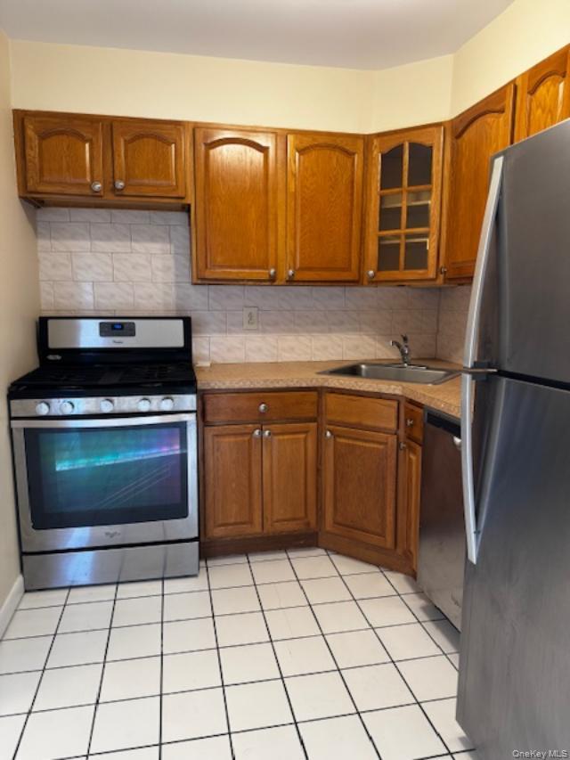 150-40 Tahoe Street, Unit 3C Queens, NY 11417 - Photo 4 of 18 Kitchen with appliances with stainless steel finishes, brown cabinetry, and backsplash