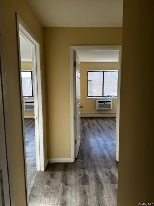 150-40 Tahoe Street, Unit 3C Queens, NY 11417 - Photo 7 of 18 Hallway featuring plenty of natural light, dark wood finished floors, a wall mounted AC, and baseboard heating