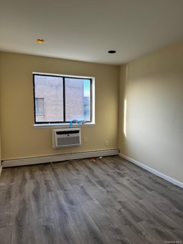 150-40 Tahoe Street, Unit 3C Queens, NY 11417 - Photo 9 of 18 Spare room featuring a baseboard radiator, dark wood-type flooring, a wall unit AC, and recessed lighting