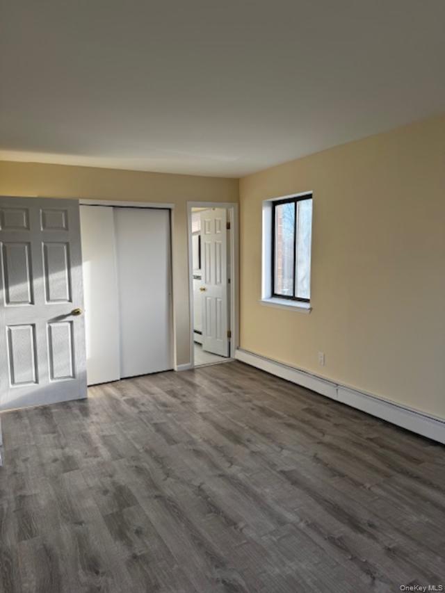 150-40 Tahoe Street, Unit 3C Queens, NY 11417 - Photo 10 of 18 Unfurnished bedroom with a baseboard heating unit, dark wood-style floors, and a closet