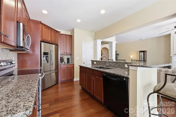 a kitchen with stainless steel appliances granite countertop a refrigerator a stove and a sink