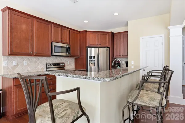 a kitchen with stainless steel appliances granite countertop a table chairs microwave and sink