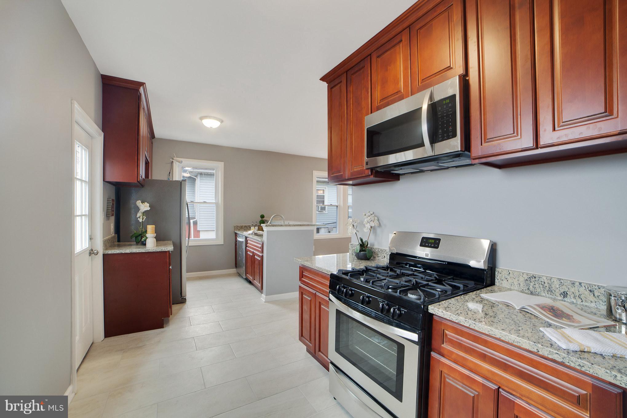 114 West Edgevale Road Baltimore, MD 21225 - Photo 9 of 22 a kitchen with stainless steel appliances granite countertop a stove top oven a sink dishwasher and a microwave oven on the blue kitchen countertops