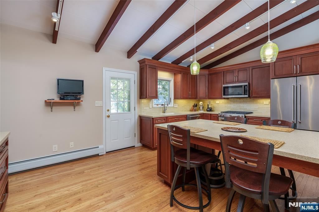 12 Ledgewood Terrace Butler, NJ 07405 - Photo 9 of 34 a kitchen with stainless steel appliances granite countertop a stove a refrigerator a microwave oven with a dining table and chairs with wooden floor