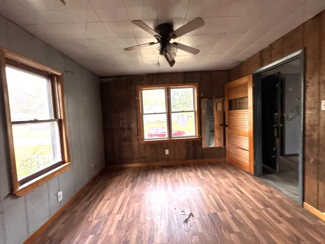 a view of an empty room with a window and wooden floor