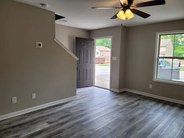 an empty room with windows and chandelier fan