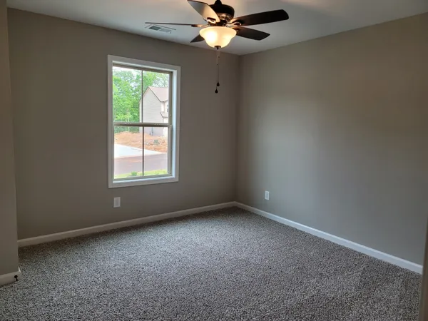 an empty room with a window and a fan