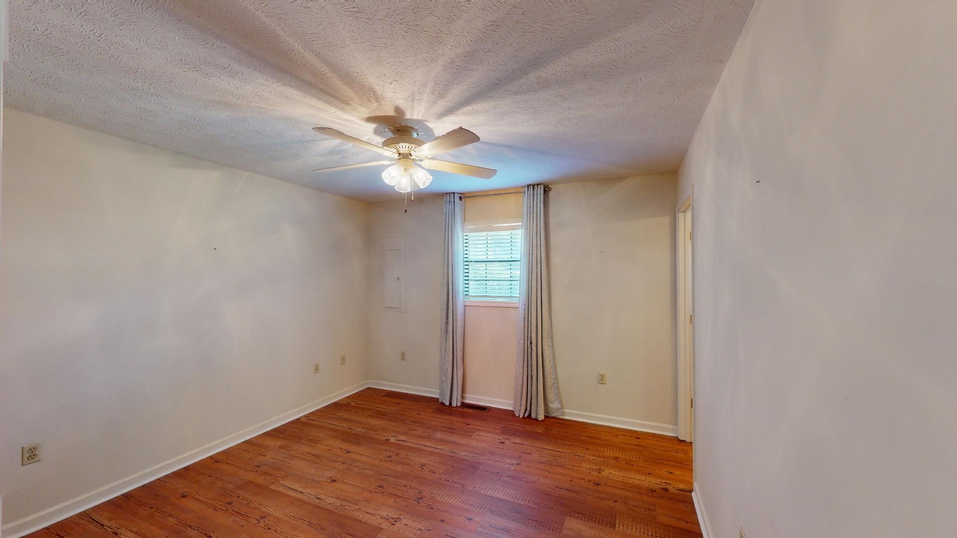 54 Whispering Lane Counce, TN 38326 - Photo 18 of 35 an empty room with wooden floor and windows
