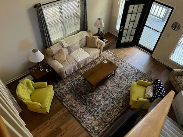 a view of a hallway with wooden floor and a bathroom