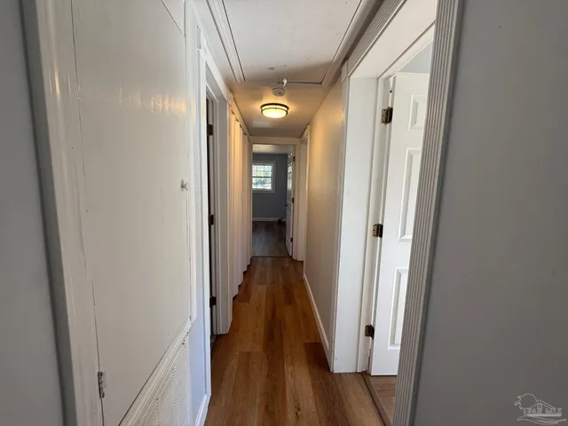 a view of a hallway with wooden floor and a bathroom