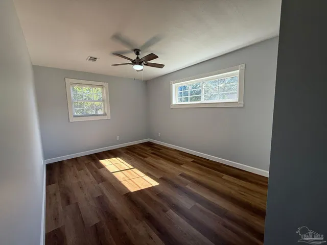 a view of empty room with wooden floor and fan
