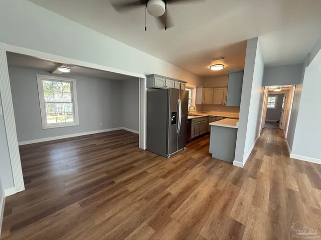 a view of a kitchen with refrigerator and wooden floor