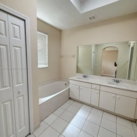 a spacious bathroom with a granite countertop sink a mirror and a bathtub