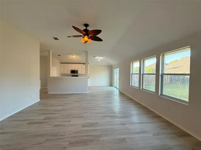 a view of an empty room with a window and wooden floor