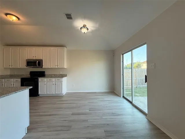 a view of kitchen with granite countertop stainless steel appliances counter space and wooden floor