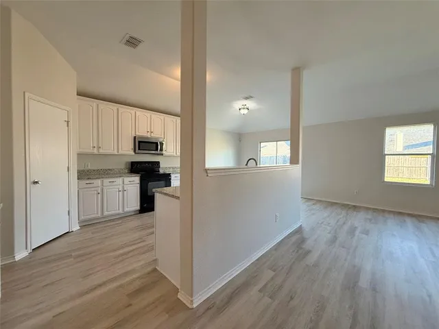 a view of a kitchen with wooden floor electronic appliances and window