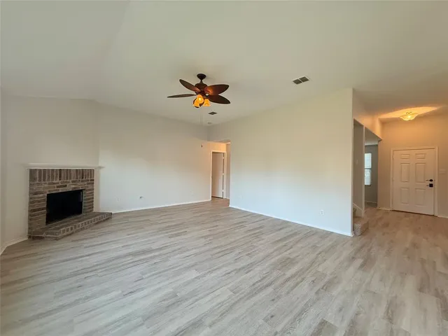 a view of empty room with wooden floor and fireplace