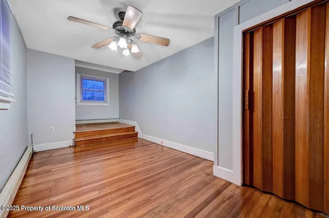 a view of empty room with wooden floor and fan