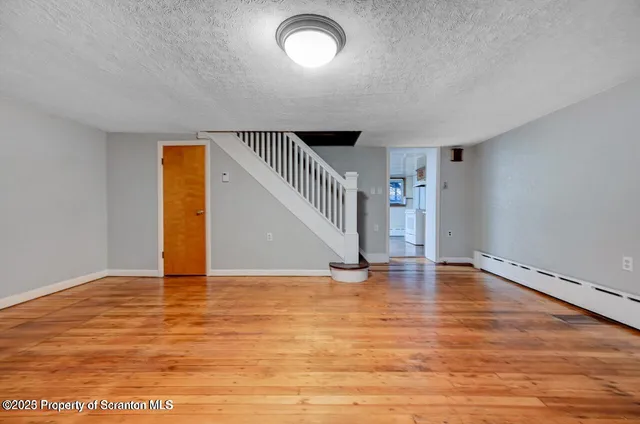 a view of an empty room with wooden floor and stairs