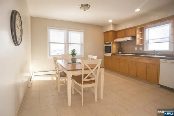 a dining room with stainless steel appliances a table and chairs in it