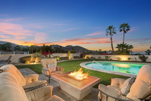 a view of a swimming pool and lounge chairs in back of a house