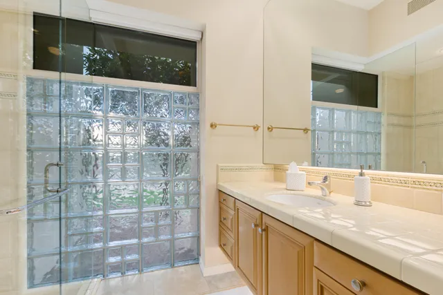 a bathroom with a granite countertop sink a mirror and shower