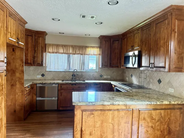 a kitchen with kitchen island granite countertop a sink stove and cabinets