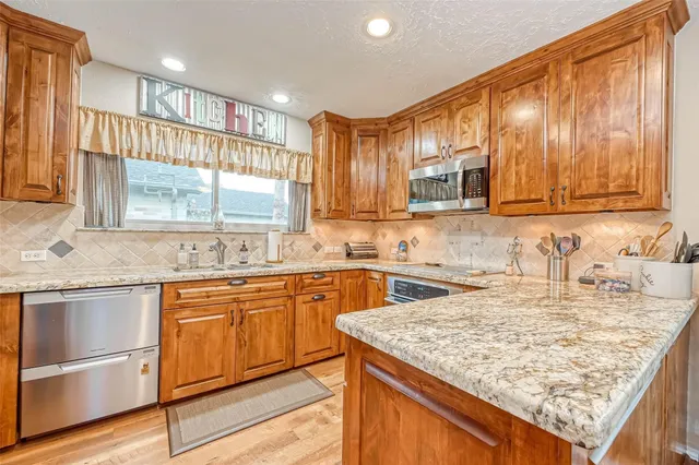 a kitchen with kitchen island granite countertop wooden cabinets a sink and dishwasher