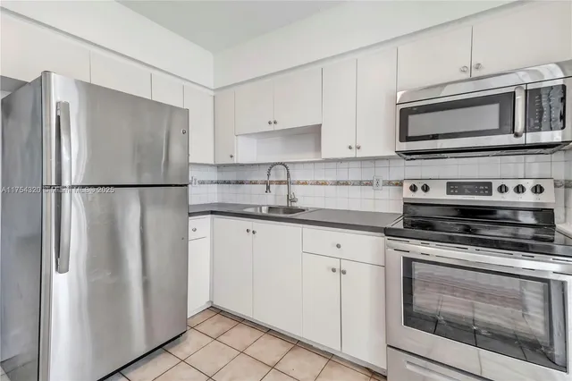a kitchen with stainless steel appliances white cabinets white stove a microwave and a refrigerator