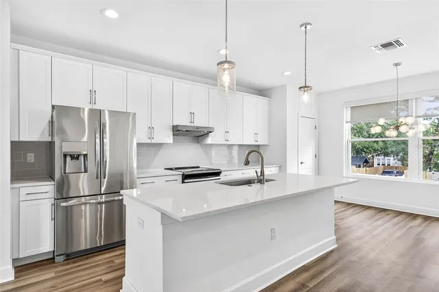 a kitchen that has a lot of cabinets a sink and wooden floor