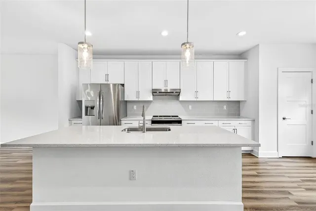 a kitchen with stainless steel appliances a sink a stove and a refrigerator with wooden floor