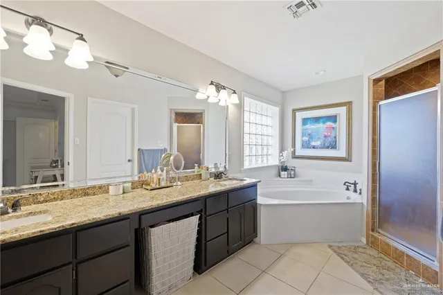 a bathroom with a sink double vanity granite tub shower and a mirror