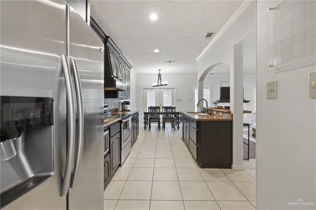 a kitchen with stainless steel appliances kitchen island granite countertop a refrigerator a stove and a sink