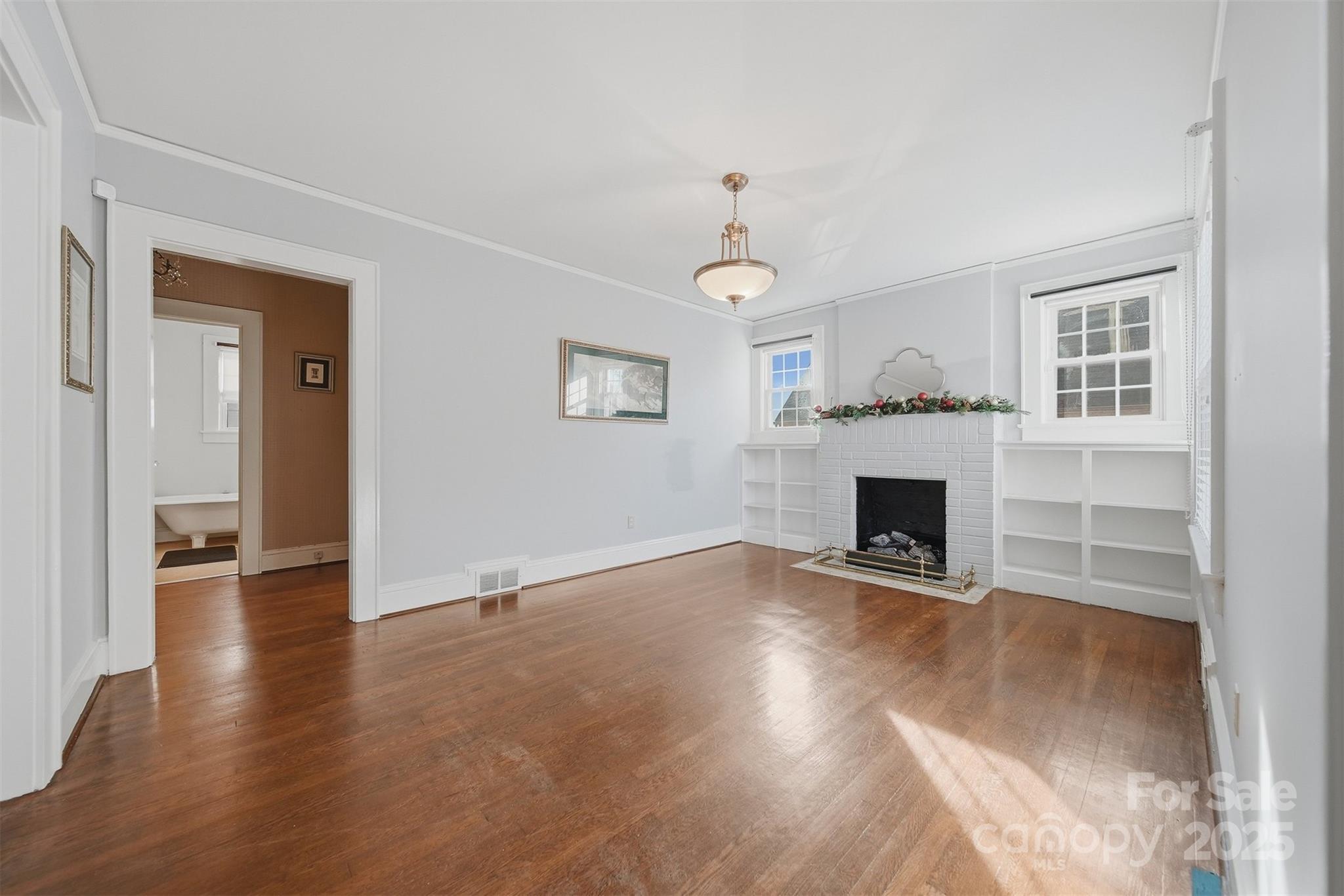 323 4th St Place Southwest Hickory, NC 28602 - Photo 4 of 32 an empty room with wooden floor fireplace and windows