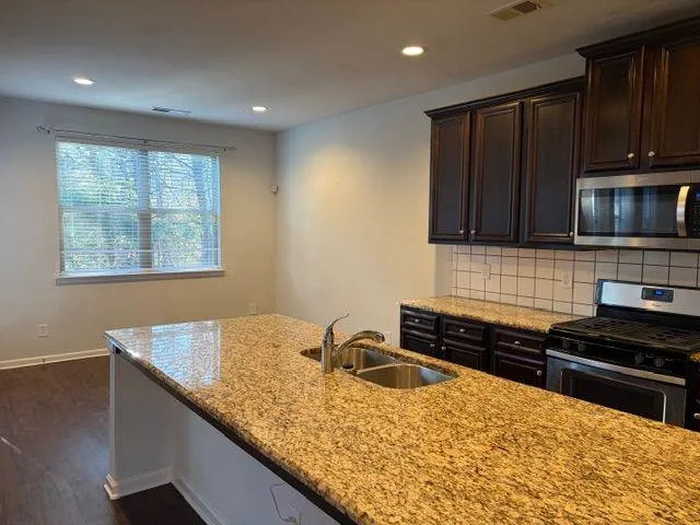 a kitchen with kitchen island granite countertop a sink a stove and a refrigerator