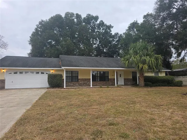 front view of house with yard and trees in the background