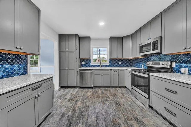 a kitchen with stainless steel appliances granite countertop a sink cabinets and wooden floor