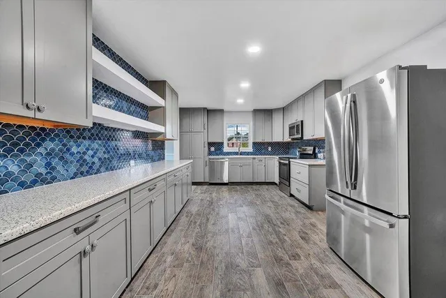 a large kitchen with stainless steel appliances granite countertop a lot of cabinets and wooden floor