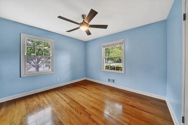 a view of empty room with wooden floor and ceiling fan