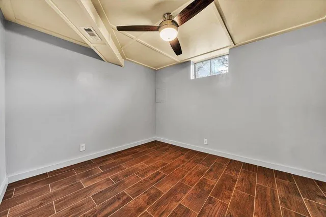 a view of empty room with wooden floor and fan