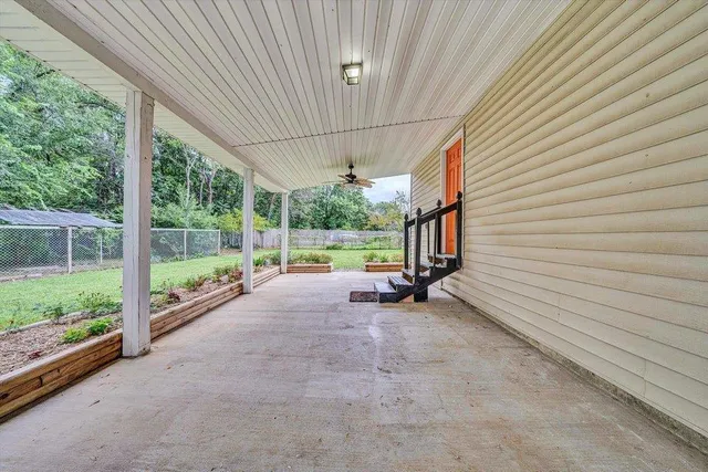 a view of patio with table and chairs and floor to ceiling window with garden