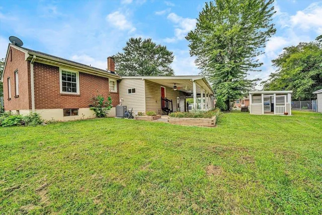 a backyard of a house with plants and large tree