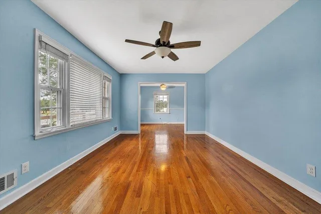 a view of empty room with wooden floor and fan