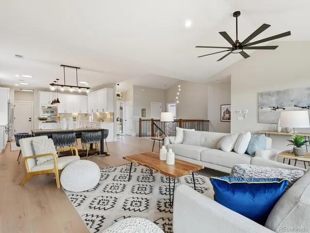a living room with furniture a kitchen view and a chandelier