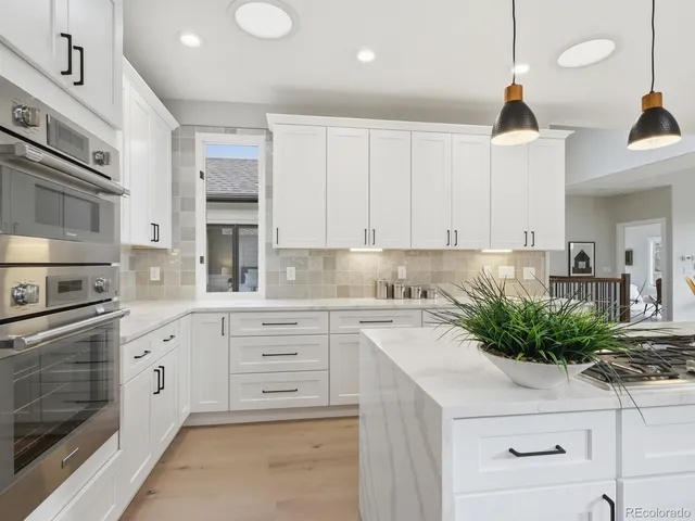 a kitchen with granite countertop white cabinets and white stainless steel appliances