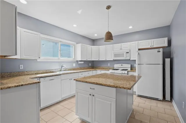 a kitchen with a sink a refrigerator and white cabinets