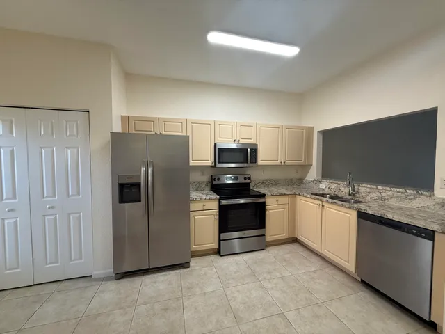 a kitchen with stainless steel appliances granite countertop a refrigerator and a stove top oven